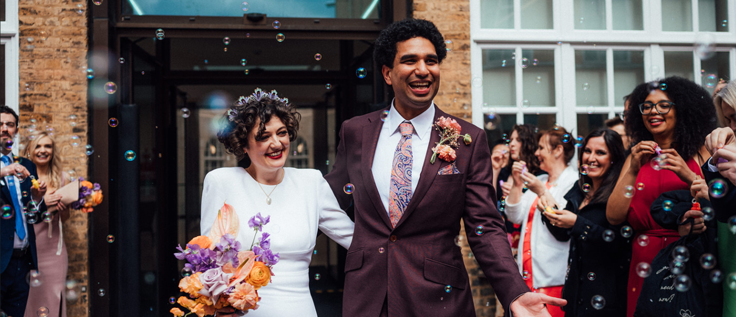 happy couple walking through guests with bubbles in air