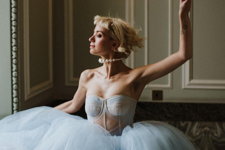 Female woman in fashion editorial shot leaping in blue dress against romantic backdrop