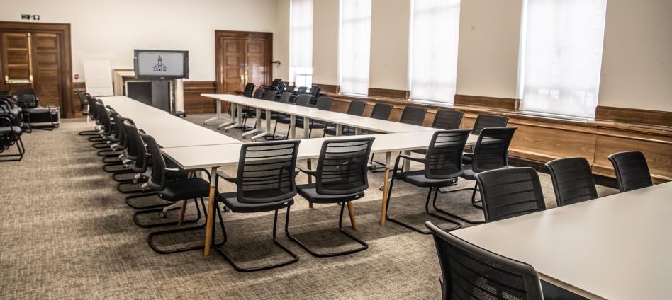 boardroom style set up with black chairs and white tables