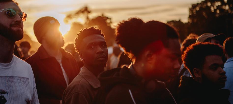 crowds standing at live music event with sun setting behind