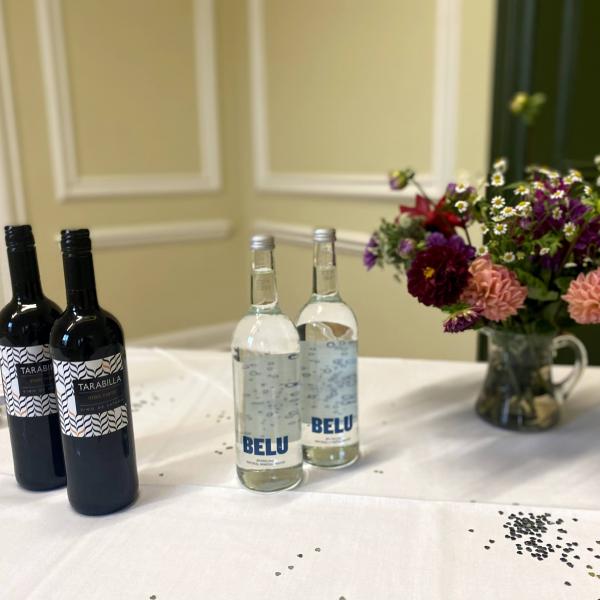 Wine and water bottles on a white table with pink and purple flowers