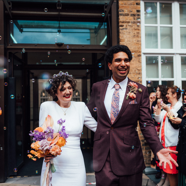 happy couple walking through guests with bubbles in air