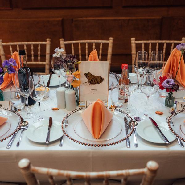 wedding tables dressed with orange napkins and purple flowers