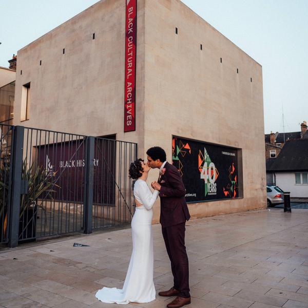 couple on wedding day against backdrop of Brixton Cultural Archives 