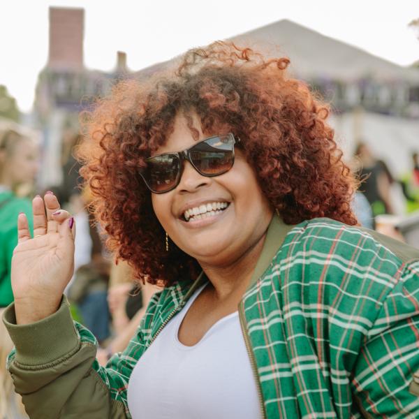 person smiling and dancing in green checked shirt and sunglasses