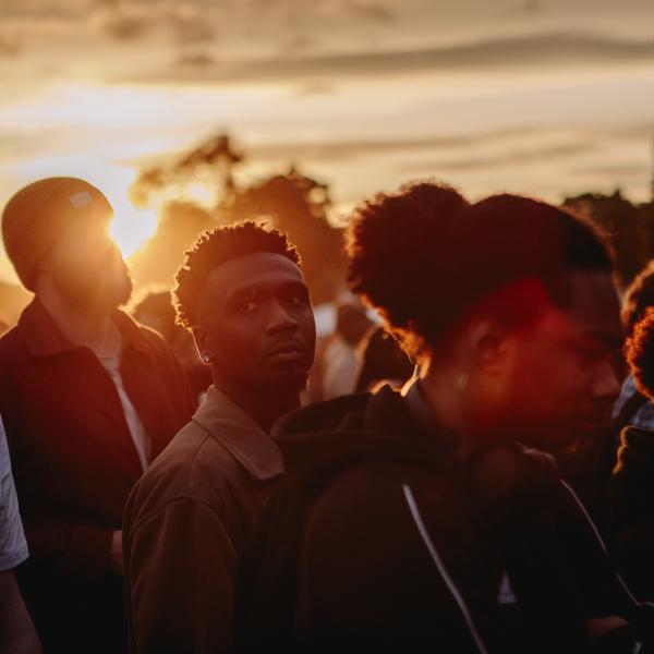 crowds standing at live music event with sun setting behind